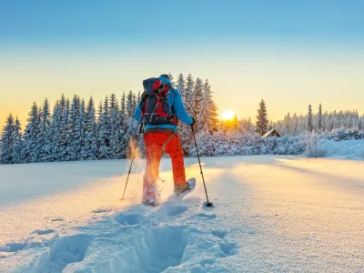 Snowshoe walker running in powder snow with beautiful sunrise light. Outdoor winter activity and healthy lifestyle