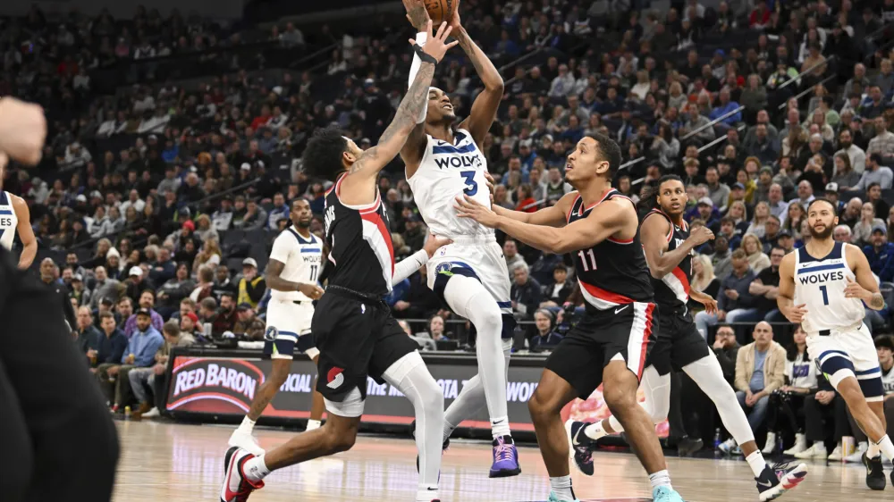 Minnesota Timberwolves forward Jaden McDaniels (3) drives to the basket between Portland Trail Blazers guard Anfernee Simons, left, and guard Malcolm Brogdon (11) during the second half of an NBA basketball game Friday, Jan. 12, 2024, in Minneapolis. (AP Photo/Craig Lassig)