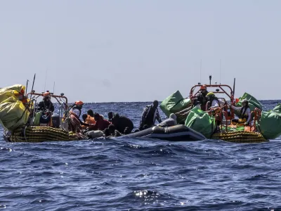 Migrants are helped evacuate a partially deflated rubber dinghy by the rescue personnel of the SOS Mediterranee humanitarian ship Ocean Viking in the Central Mediterranean Sea, Wednesday, March 13, 2024. Survivors reported that some 50 people who departed Libya with them a week ago had perished during the journey. (Johanna de Tessieres/ SOS Mediterranee via AP, HO)