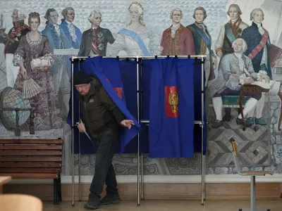 A man leaves a voting booth at a polling station located in a school during the presidential elections in St. Petersburg, Russia, Saturday, March 16, 2024, with a painting depicting the Russian Tsarina Catherine II and her contemporaries on the wall. Voters in Russia are heading to the polls for a presidential election that is all but certain to extend President Vladimir Putin's rule after he clamped down on dissent. (AP Photo/Dmitri Lovetsky)
