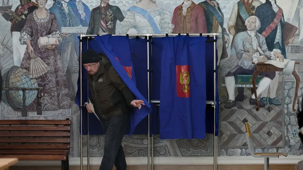 A man leaves a voting booth at a polling station located in a school during the presidential elections in St. Petersburg, Russia, Saturday, March 16, 2024, with a painting depicting the Russian Tsarina Catherine II and her contemporaries on the wall. Voters in Russia are heading to the polls for a presidential election that is all but certain to extend President Vladimir Putin's rule after he clamped down on dissent. (AP Photo/Dmitri Lovetsky)