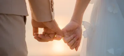 The bride and groom use the little finger together. lovely couple hold hand with sunset background