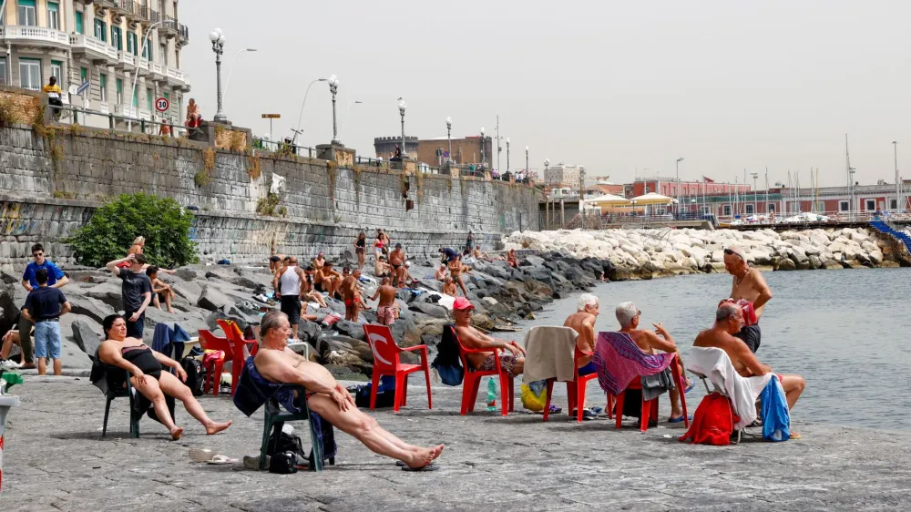 People sunbathe at the beach during a heatwave in Naples, Italy, June 21, 2024. REUTERS/Ciro De Luca