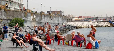 People sunbathe at the beach during a heatwave in Naples, Italy, June 21, 2024. REUTERS/Ciro De Luca