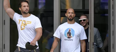 FILE - Andrew Tate, center, and his brother Tristan, left, exit the Bucharest Tribunal after being placed under house arrest, in Bucharest, Romania, Aug. 22, 2024. (AP Photo/Alexandru Dobre, File)