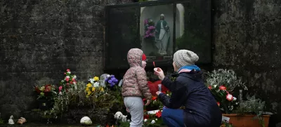 Denise Gormley and her daughter Rosa, 7, pay their respects and blow bubbles at the Tuam graveyard, where the bodies of 796 babies were uncovered at the site of a former Catholic home for unmarried mothers and their children, on the day a government-ordered inquiry into former Church-run homes for unmarried mothers is formally published, in Tuam, Ireland, January 12, 2021. REUTERS/Clodagh Kilcoyne
