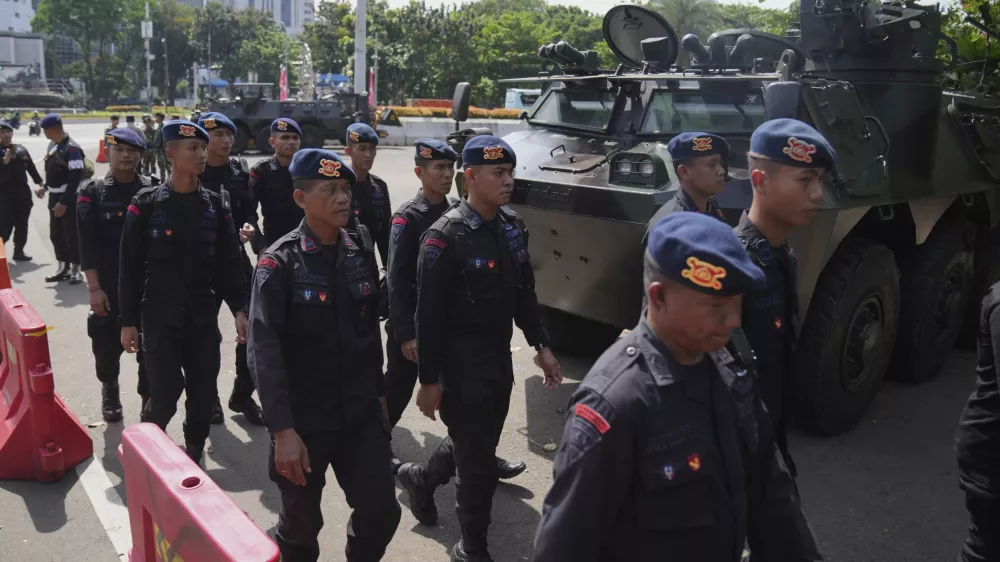 Members of Indonesian police's paramilitary unit Mobile Brigade walk past army armored vehicles parked near the National Monument following days of violent protests against lavish allowances given to parliament members, in Jakarta, Indonesia, Tuesday, Sept. 2, 2025. (AP Photo/Dita Alangkara)