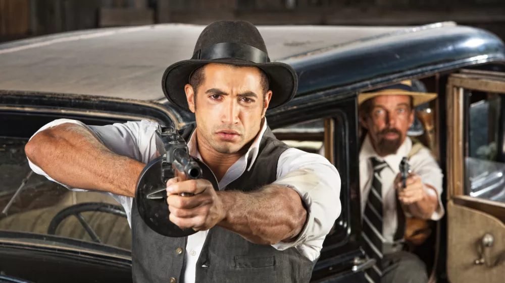Tough 1920s vintage gangsters by car with weapons / Foto: Creatista