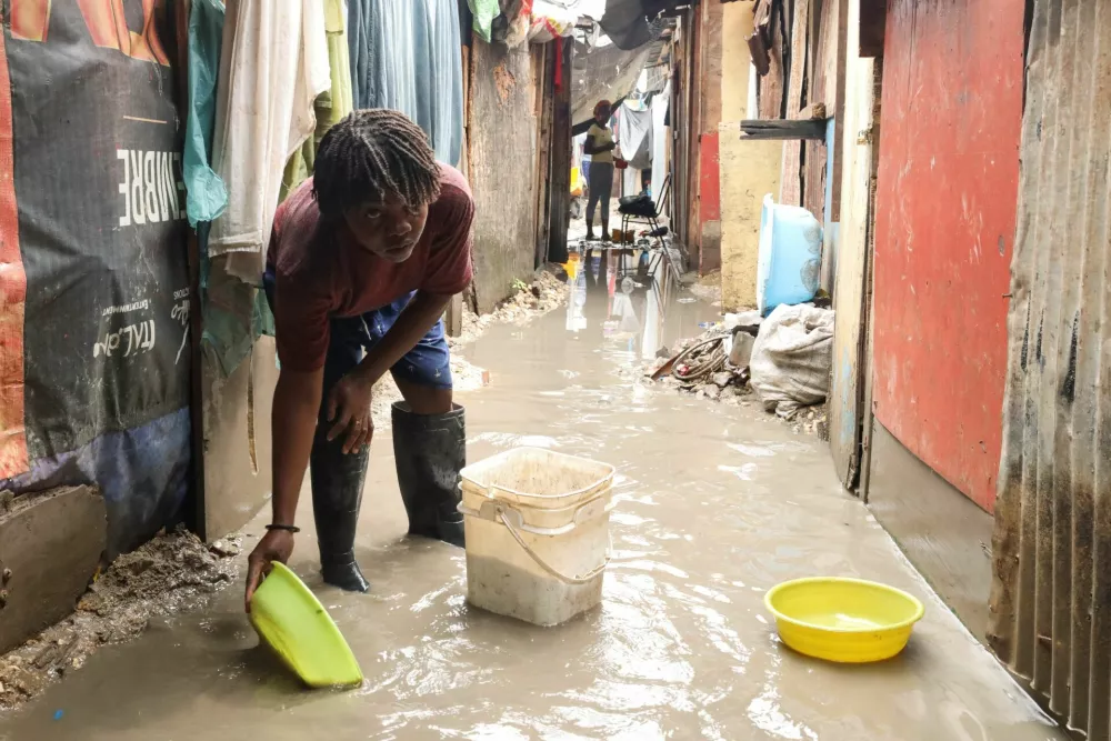 A person scoops water from the ground to lower the water levels, after floods caused by the outer bands of Hurricane Melissa killed several people, in Petit Goave, Haiti, October 29, 2025. REUTERS/Egeder Pq Fildor