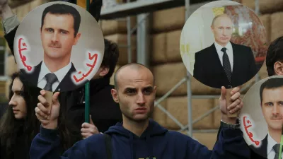 A man holds portrait of Russia's President Vladimir Putin (R) and Syria's President Bashar al-Assad (L) during a rally in support of Syrian regime in front of the US Embassy in Moscow, on October 19, 2012. Moscow has defiantly refused to take sides against Assad, and has slammed the West and Turkey for making clear their support for the rebels battling his regime.,Image: 144327568, License: Rights-managed, Restrictions:, Model Release: no