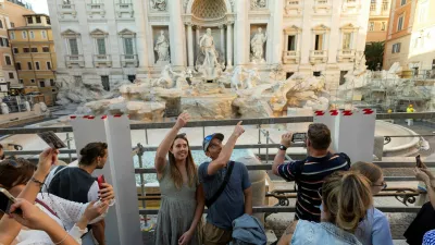 FILE PHOTO: People throw coins and wishes inside a pool as Trevi Fountain undergoes maintenance works in Rome, Italy, October 31, 2024. REUTERS/Remo Casilli/File Photo