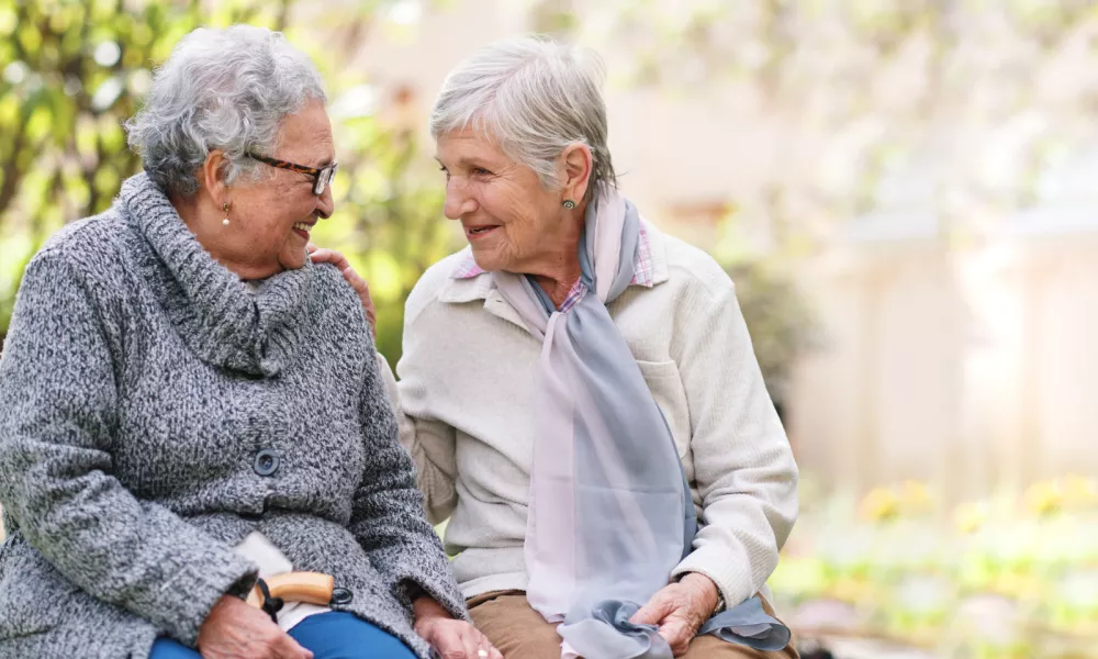 Two elderly women sitting on bench in park smiling happy life long friends enjoying retirement / Foto: Jacob Wackerhausen