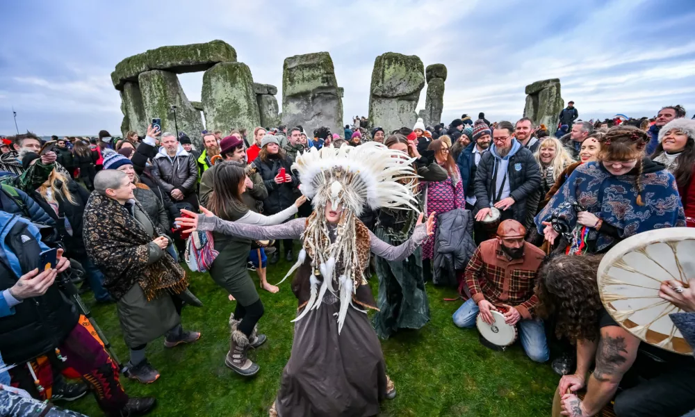 Kefan Wang, a shaman from China and Abbie Coombs from London dancing as people celebrate the Winter Solstice sunrise celebrations at Stonehenge, a world-famous prehistoric monument on Salisbury Plain, England, Sunday, Dec. 21, 2025. (AP Photo/Anthony Upton)