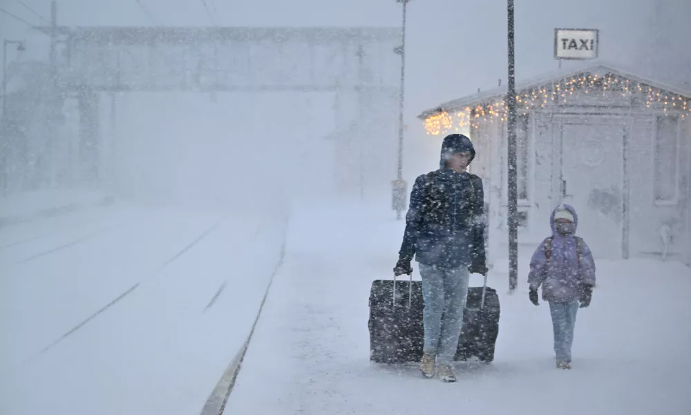 People walk under heavy snow as departures are cancelled at the train station in Are, Sweden, Saturday Dec. 27, 2025. (Pontus Lundahl/TT News Agency via AP)