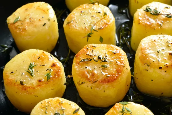 Fondant potatoes in frying pan over wooden table. Close up view / Foto: Tatiana Volgutova