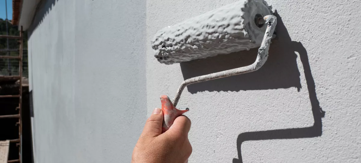 Painter's hand holding a roller filled with paint to paint an exterior wall / Foto: Leirao, Getty Images