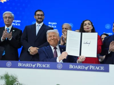 President Donald Trump, center, holds up a signed Board of Peace charter during the Annual Meeting of the World Economic Forum in Davos, Switzerland, Thursday, Jan. 22, 2026. (AP Photo/Evan Vucci)