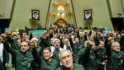 In this handout photo released by the Islamic Consultative Assembly News Agency (ICANA) Iranian lawmakers chant slogans as they wear the Revolutionary Guard's uniform in a session of parliament, in Tehran, Iran, Sunday, Feb. 1, 2026. (Hamed Malekpour/ICANA via AP)