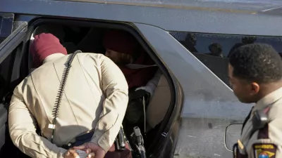 A Minnesota state policeman speaks to a woman sitting inside an ICE vehicle after she was briefly detained on Interstate 35W by Federal immigration agents while they conduct immigration enforcement tasks in Minneapolis, Minnesota, U.S., February 3, 2026. REUTERS/Seth Herald