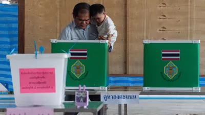 08 February 2026, Thailand, Bangkok: A man hoding a kid casts his ballot at a polling station during the general elections in Bangkok. Thailand's 53 million eligible voters are to elect a new parliament on Sunday, while also determining in a referendum whether to initiate the formation of a new national constitution. Photo: Peerapon Boonyakiat/SOPA Images via ZUMA Press Wire/dpa