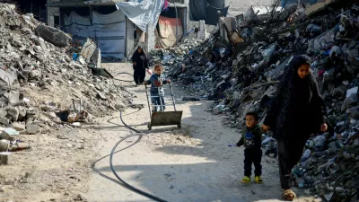 FILE PHOTO: Palestinians walk past the rubble of residential buildings destroyed during the war, in Jabalia, northern Gaza Strip, January 6, 2026. REUTERS/Mahmoud Issa/File Photo