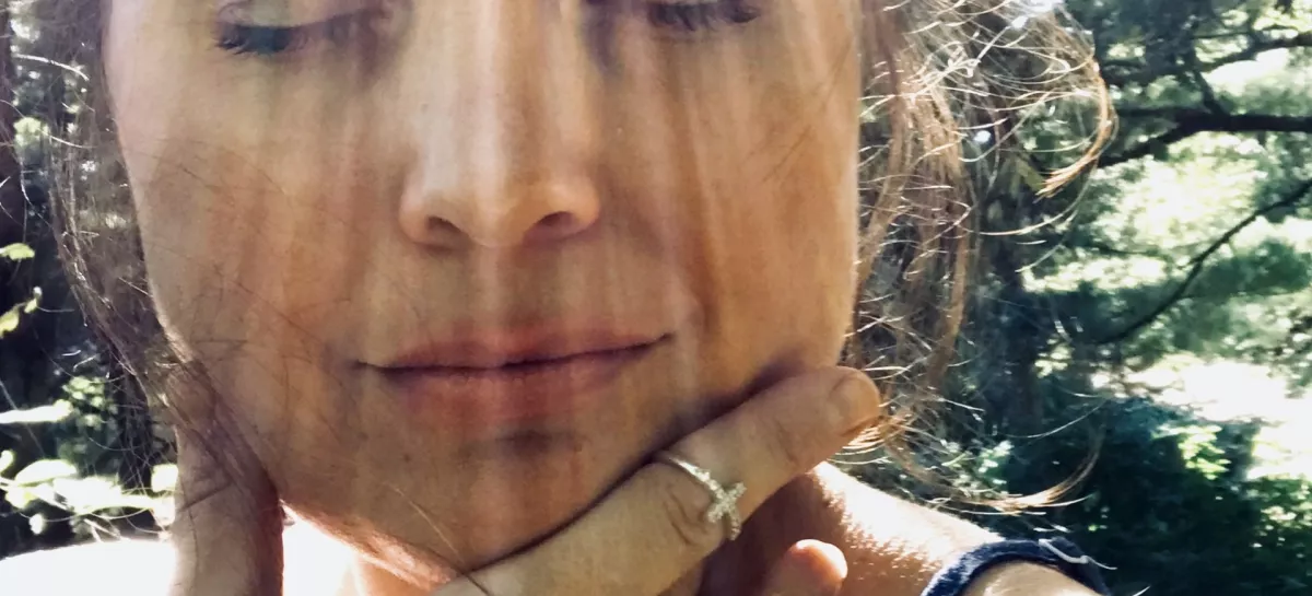 Beautiful middle aged woman, a portrait shot of face only, model is outside in the sun, with very distinct rays of sunlight making dramatic ray marks on her face. Her eyes are closed in relaxation and happiness, feeling the warmth. Model has dark brown, upswept hair and an off the shoulder top. / Foto: Jamie Casper
