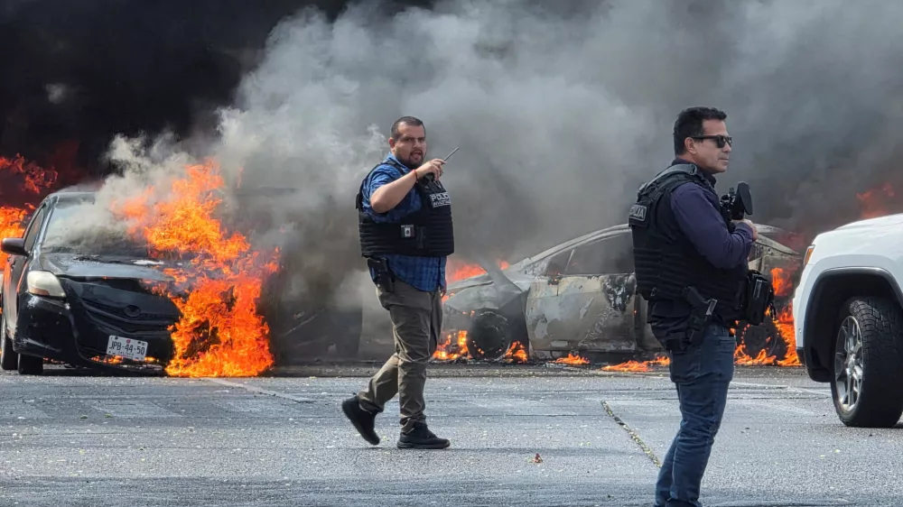 Police officers secure the area where vehicles were set on fire by organized crime members to block a road following a military operation in which a government source said Mexican drug lord Nemesio Oseguera, commonly known as "El Mencho," was killed, in Zapopan, Mexico, February 22, 2026. REUTERS/Gilberto Gallo   TPX IMAGES OF THE DAY
