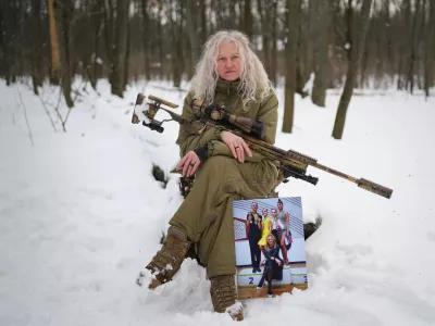 Tetiana Khimion 47, now a sniper in the Ukrainian army, poses with a photograph of herself as a dance teacher taken before Russia's full-scale invasion, in a park in Kyiv, Ukraine, Sunday, Feb. 22, 2026. (AP Photo/Sergei Grits)
