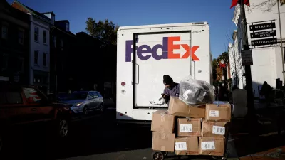 FILE PHOTO: A driver of FedEx stands with packages near a delivery truck during Black Friday preparations in the Georgetown neighborhood of Washington, U.S., November 26, 2024. REUTERS/Benoit Tessier/File Photo