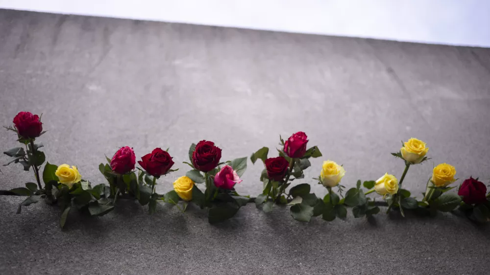 Flowers pile up in a crack in the Berlin Wall for the victims of the German division during an event to mark the 34th anniversary of the fall of the Berlin Wall at the Berlin Wall Memorial, Thursday, Nov. 9, 2023. (AP Photo/Markus Schreiber) / Foto: Markus Schreiber