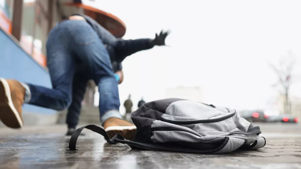 Close-up of person get injury after falling on slippery ground in winter season. Personal backpack lay on asphalt ice. Accident, trauma, clumsy concept / Foto: Ivan-balvan Getty Images