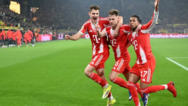 Bayern Munich's Joshua Kimmich, centre, celebrates with Josip Stanisic and Michael Olise after scoring his side's third goal during the Bundesliga soccer match between Borussia Dortmund and FC Bayern Munich in Dortmund, Germany, Saturday Feb. 28, 2026. (Federico Gambarini/dpa via AP)