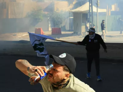 A person washes his face with a soft drink bottle after riot police deployed irritants to disperse protesters supporting Iraqi Shi'ite armed groups gathered near the entrance of the Green Zone and attempted to move toward the U.S. embassy after the killing of Iran's Supreme Leader Ayatollah Ali Khamenei, in Baghdad, Iraq, March 1, 2026. REUTERS/Thaier Al-Sudani   TPX IMAGES OF THE DAY