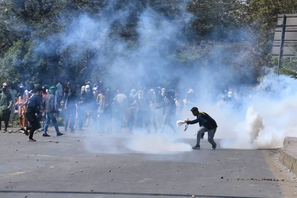 Shiite Muslims run for cover after police fire tear gas shell to disperse them during a protest to condemn the killing of Iranian Supreme Leader Ayatollah Ali Khamenei, in Karachi, Pakistan, Sunday, March 1, 2026. (AP Photo/Ali Raza)