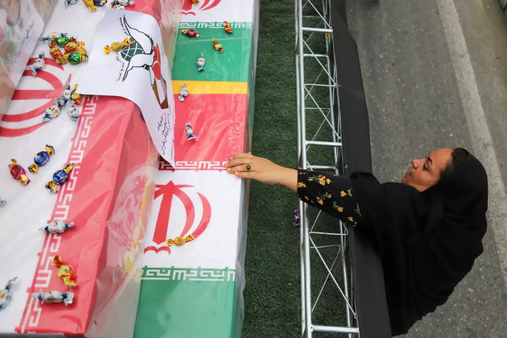 A woman reaches out to the coffins during funeral of mostly children killed in what Iranian officials said was an Israeli-U.S. strike Feb. 28 on a girls' elementary school in Minab, Iran, Tuesday, March 3, 2026. (Amirhossein Khorgooei/ISNA via AP)