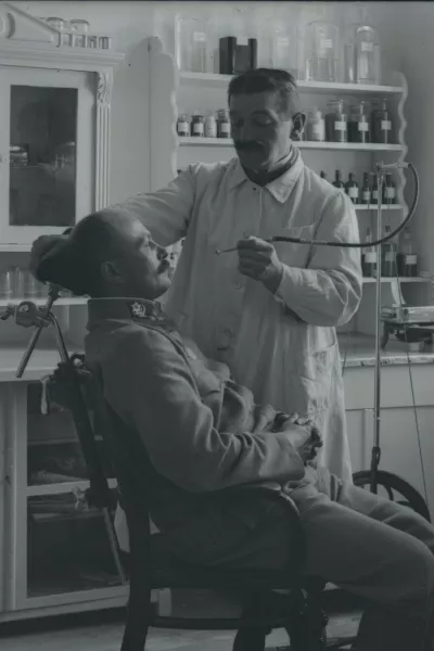 Oficir pri zobozdravniku med prvo svetovno vojno. Naglič je, čeprav je bil zaprt na Ljubljanskem gradu v karantenski postaji, začuda lahko prosto fotografiral in tako ohranil edinstvene prizore voja&scaron;kega vsakdana. / Foto: Peter Naglič