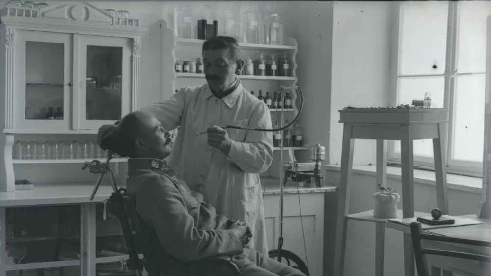 Oficir pri zobozdravniku med prvo svetovno vojno. Naglič je, čeprav je bil zaprt na Ljubljanskem gradu v karantenski postaji, začuda lahko prosto fotografiral in tako ohranil edinstvene prizore voja&scaron;kega vsakdana. / Foto: Peter Naglič