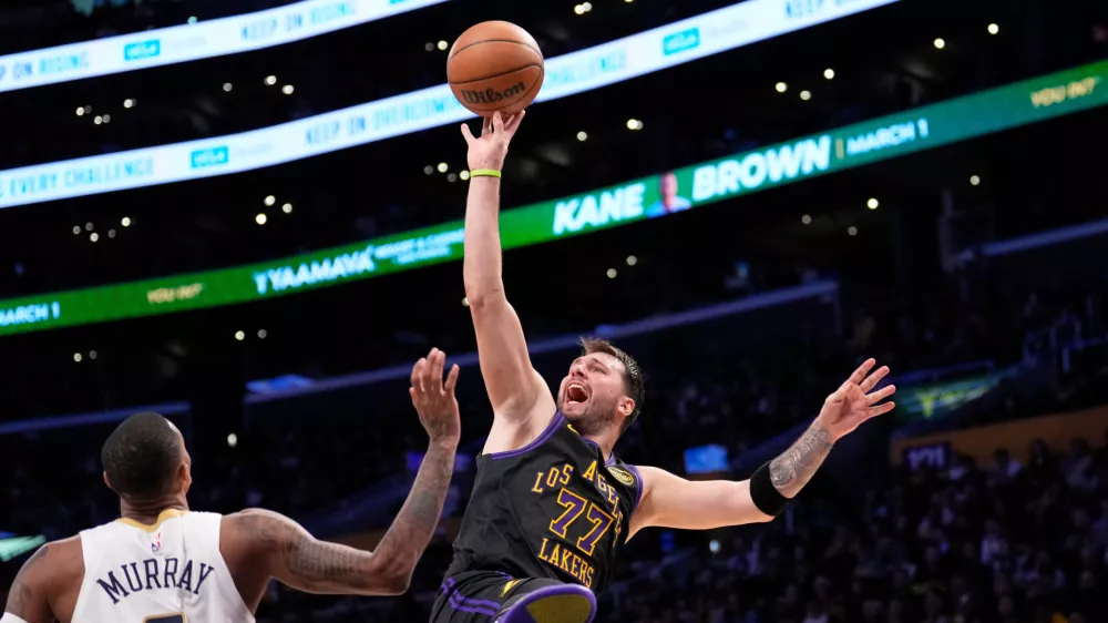 Los Angeles Lakers guard Luka Doncic, right, shoots as New Orleans Pelicans guard Dejounte Murray defends during the second half of an NBA basketball game Tuesday, March 3, 2026, in Los Angeles. (AP Photo/Mark J. Terrill)