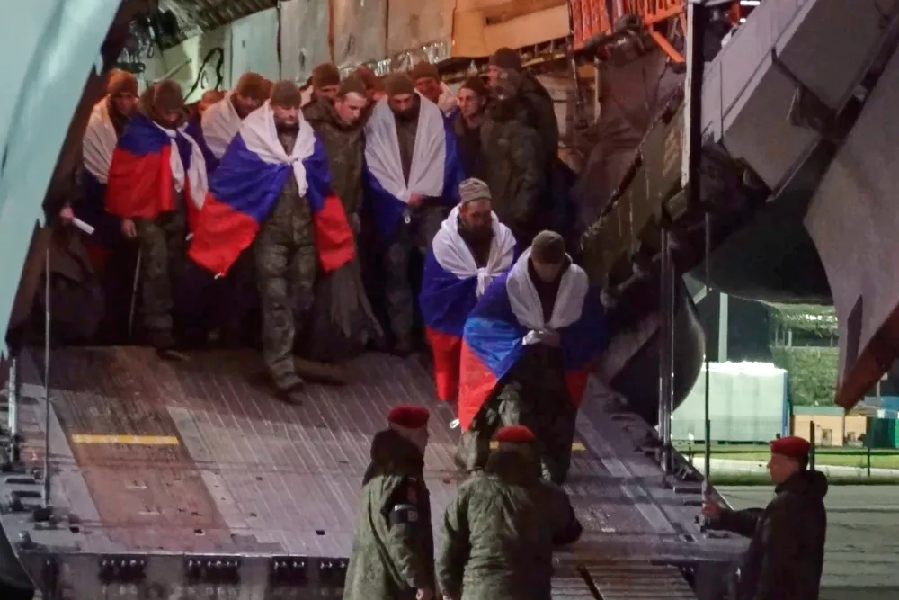 In this photo, taken from a video and distributed by the Russian Defense Ministry Press Service on Thursday, Oct. 2, 2025, Russian servicemen hold Russian national flags leaving a plain after returning from captivity during a POWs exchange of a group of servicemen between Russia and Ukraine in an airport outside Moscow. (Russian Defense Ministry Press Service via AP)