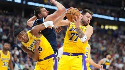 Los Angeles Lakers guard Luka Dončić, right, pulls in a rebound as forward Rui Hachimura, left, boxes out Denver Nuggets center Nikola Jokić in the second half of an NBA basketball game Thursday, March 5, 2026, in Denver. (AP Photo/David Zalubowski)