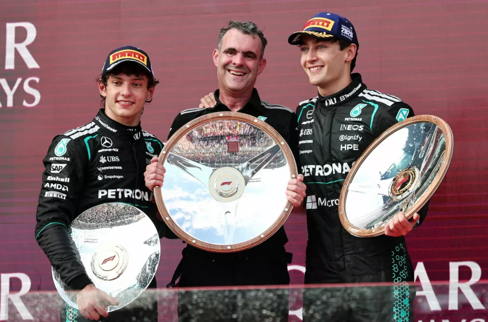 Formula One F1 - Australian Grand Prix - Albert Park Grand Prix Circuit, Melbourne, Australia - March 8, 2026 Mercedes' George Russell celebrates on the podium after winning the Australian Grand Prix alongside second placed Mercedes' Andrea Kimi Antonelli and mercedes f1 power unit manager Hywel Thomas REUTERS/Mark Peterson