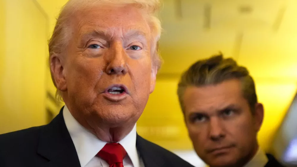 President Donald Trump speaks to reporters as Defense Secretary Pete Hegseth listens while traveling aboard Air Force One en route from Dover Air Force Base, Del., to Miami, Saturday, March 7, 2026. (AP Photo/Mark Schiefelbein)