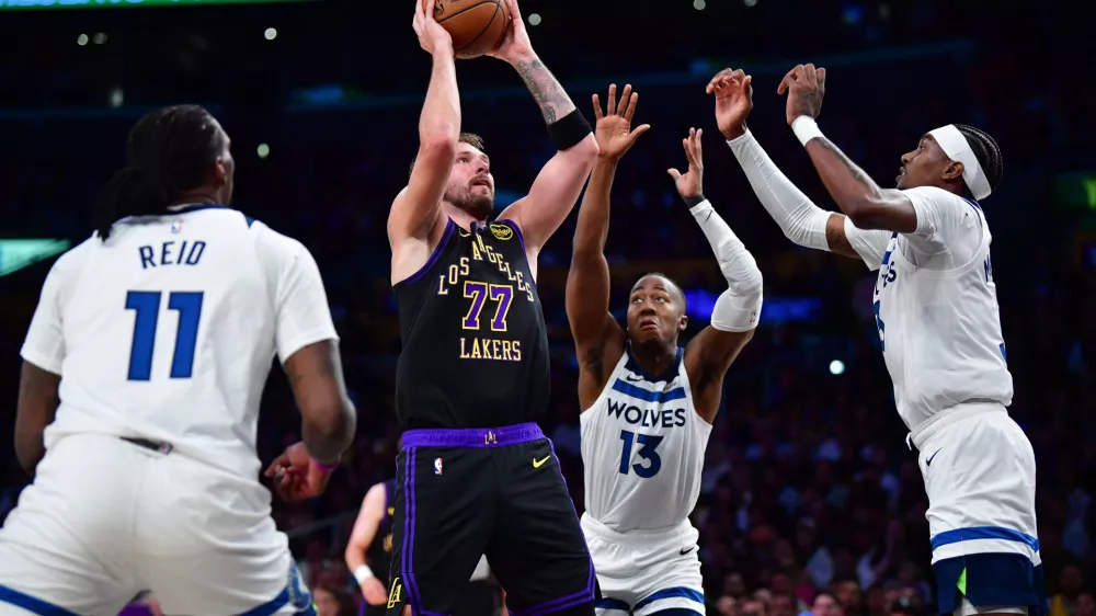 Mar 10, 2026; Los Angeles, California, USA; Los Angeles Lakers guard Luka Doncic (77) shoots against the defense of Minnesota Timberwolves center Naz Reid (11) guard Ayo Dosunmu (13) and forward Jaden McDaniels (3) during the first half at Crypto.com Arena. Mandatory Credit: Gary A. Vasquez-Imagn Images