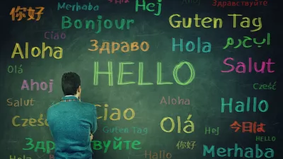 Rear view of a puzzled businessman in front of a huge chalkboard written with the word hallo in different languages and colors. Opportunity for learning many languages for students.