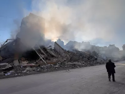 A man passes in front of a destroyed building that housed a branch of Al-Qard Al-Hassan, a non-bank financial institution run by Hezbollah, which was hit by an Israeli airstrike in Dahiyeh, Beirut's southern suburbs, Lebanon, Tuesday, March 10, 2026. (AP Photo/Hussein Malla)