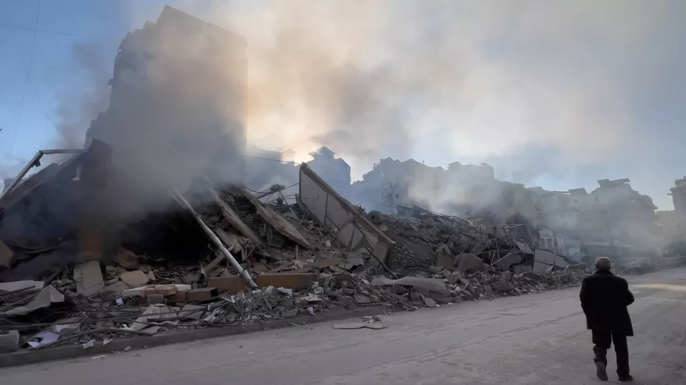 A man passes in front of a destroyed building that housed a branch of Al-Qard Al-Hassan, a non-bank financial institution run by Hezbollah, which was hit by an Israeli airstrike in Dahiyeh, Beirut's southern suburbs, Lebanon, Tuesday, March 10, 2026. (AP Photo/Hussein Malla)