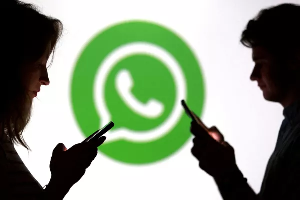 FILE PHOTO: Teenagers pose for a photo while holding smartphones in front of a Whatsapp logo in this illustration taken September 11, 2025. REUTERS/Dado Ruvic/Illustration/File Photo