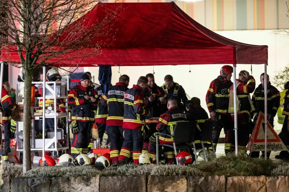 Firemen gather next to the charred shell of a postal bus, not pictured, which caught fire killing several people and injuring others, in Kerzers, Switzerland, Tuesday, March 10, 2026. (Alessandro della Valle/Keystone via AP)