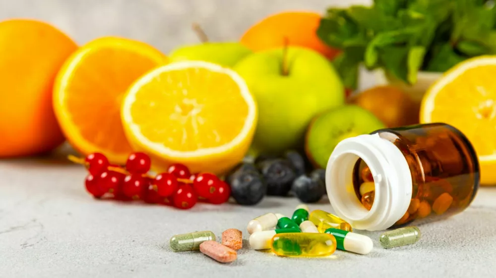 Vitamins and supplements. Variety of vitamin tablets in a jar on a texture background.Multivitamins with fresh and healthy fruits.Food supplements. Flat lay. Space for text.Copy space