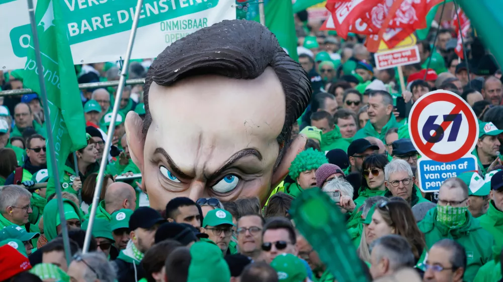 Protestors wheel a giant puppet head depicting Belgium's Prime Minister Bart De Wever and hold signs which read "hands off our pensions" as they demonstrate during general strike actions in Brussels, Thursday, March 12, 2026. (AP Photo/Geert Vanden Wijngaert)